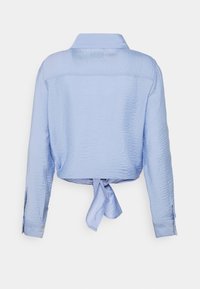 Ljusblåt avkortad skjorta i strukturerad tyg, långa ärmar, krage och knytning i midjan. Har knäppta manschetter.