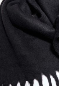 Sort uldhalstørklæde med en blød tekstur, der har frynser i kanterne. Stoffet ser tæt og varmt ud, med en glat, mat overflade.