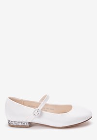 Białe buty typu Mary Jane z okrągłym czubkiem, pojedynczym paskiem z klamerką i niskim błyszczącym srebrnym obcasem w kształcie bloku.
