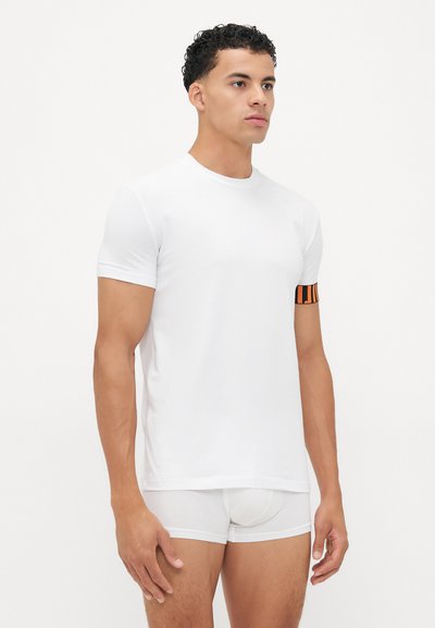 White short-sleeve t-shirt with a round neck and an orange and black striped armband on the left sleeve. Smooth texture.