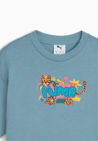 Blå bomulds T-shirt med et farverigt grafisk motiv af en leopard med legende accenter og "PUMA" logoet i fede bogstaver.