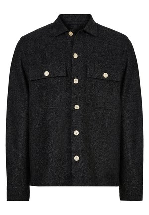 Chaqueta de camisa de patrón espiga negra hecha de tela texturizada, con cierre de botones en la parte delantera, dos bolsillos en el pecho y botones de color crema.