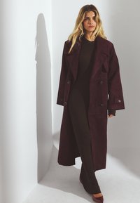 Burgundia nubukist mantli jope, topelt nuppudega, laiad kraed ja pikad varrukad, koos kehaümberkudumise pruunist ribakleidiga.