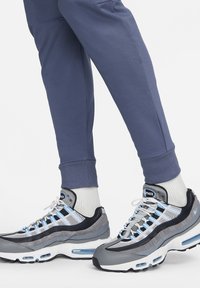 Sportieve sneakers in grijs en zwart met gaas- en suède-accenten. Kenmerken zijn blauwe details, vetersluiting en zichtbare luchtkussens.
