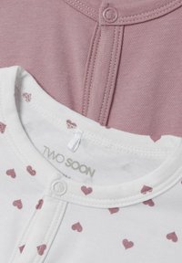 Body bébé en coton, un en rose et un en blanc avec des motifs de cœurs roses. Doté de fermetures à pression et de textures douces. Marque : Two Soon.