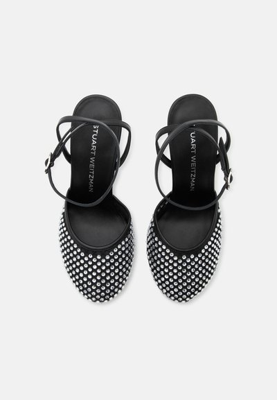 Sandales plates noires avec brides à la cheville et strass argentés couvrant la zone des orteils, vues de dessus sur fond blanc.