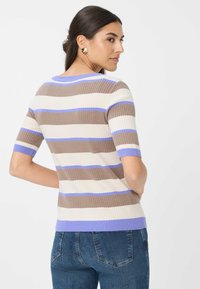 Gestreepte geribbelde gebreide top in beige, bruin en lichtblauw, met korte mouwen en een lichtblauwe kraag. Gediend met blauwe jeans.