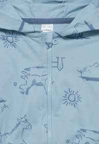 Hellblaues Zip-Up Hoodie mit einem dunkelblauen Pferdemuster, Sonnenmotiven und einer weichen Textur. Das Etikett zeigt den Markennamen "Carter's."