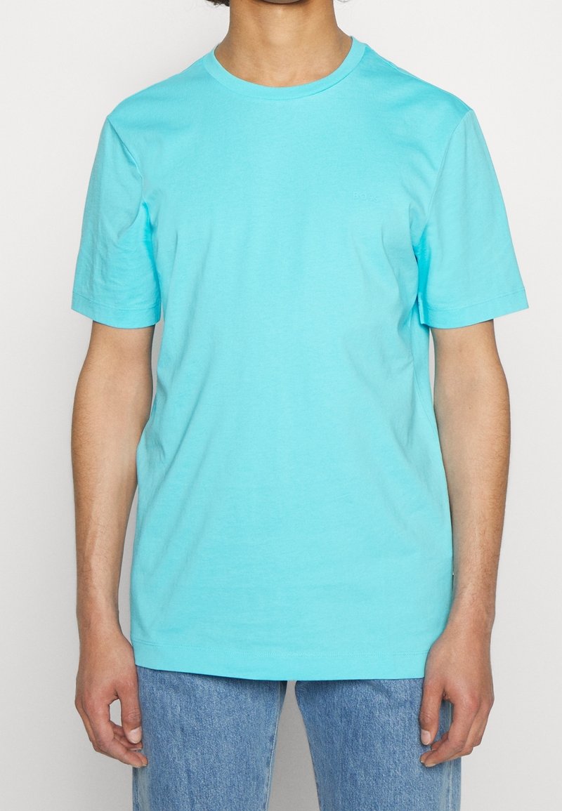 Tyrkysové bavlněné tričko s kulatým výstřihem a krátkými rukávy, se subtílním logem na hrudi a volnějším střihem.