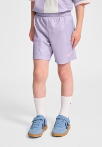 Ljuslila idrottsshorts med elastisk midja och en liten rosa logotyp. Bärs med vita strumpor och blå sneakers med kardborreband.