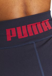 Las mallas navy cuentan con una amplia cinturilla acanalada con "PUMA" en letras rojas en negrita. El material es suave y presenta sutiles detalles de costura.