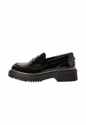 Mocassin en cuir verni noir avec semelle en caoutchouc épaisse, garniture dorée et détail de bride à souliers sur fond blanc.
