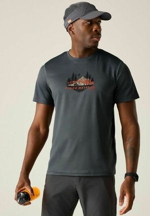 Man wearing dark gray outdoor shirt and cap, holding an orange water bottle and looking to his left.