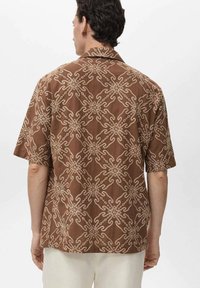 Braunes Kurzarmhemd mit geometrischem Muster in Beige. Mit Kragen, aus leichtem Stoff und in entspannter Passform.