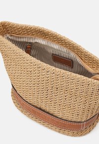 Woven straw bag with a textured surface, featuring a brown leather band and striped fabric lining. Zipper closure at the top.
