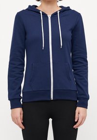 Navy zip-up hoodie made of soft fabric, featuring a hood, white drawstrings, two front pockets, and ribbed cuffs and hem.