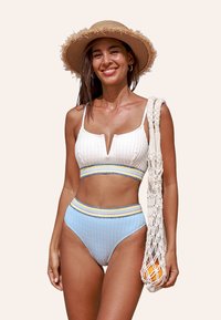 Costume da bagno a due pezzi a coste in bianco e azzurro chiaro con scollatura a V, caratterizzato da bande colorate a strisce e una parte inferiore a vita alta. Borsa a rete intrecciata.
