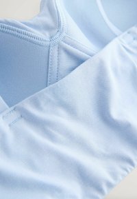 Tessuto azzurro chiaro con una trama liscia, caratterizzato da una vestibilità aderente e un design senza cuciture. Include cuciture dettagliate lungo i bordi.