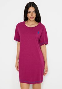 Fialová šaty z trička vyrobené z mäkkej tkaniny, s krátkymi rukávmi, okrúhlym výstrihom a modrými stehovými akcentmi na rukávoch a leme.