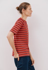 Rødstribet kortærmet t-shirt med rund halsudskæring, der har vandrette hvide og marineblå striber. Blødt, letvægtsstof, lige pasform.