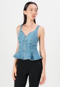 Light blue denim top with a fitted bodice, zip closure, and peplum hem. Wide shoulder straps and structured design enhance shape.