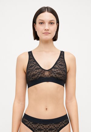 Black lace bralette featuring a deep V-neckline and wide straps. Elastic band at the bottom with a subtle logo detail. Smooth texture.