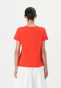 Tricou roșu cu mânecă scurtă și decolteu rotund. Fabricat dintr-un material moale, având o croială lejeră și o textură netedă. Fără logo-uri sau modele vizibile.