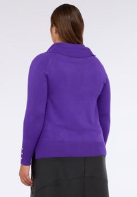 Maglione in maglia viola con un ampio colletto, dotato di maniche lunghe e dettagli con bottoni dorati vicino ai polsini. Texture liscia, design aderente.