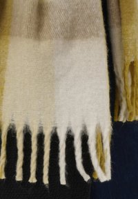 Sciarpa di lana con un motivo a quadri nei toni di giallo, beige e bianco, con estremità frangiate e una finitura morbida e testurizzata.