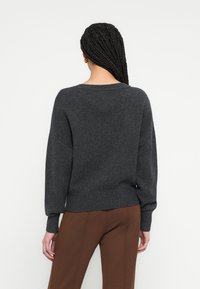 Σκούρα γκρι φαρδιά μπλούζα από απαλό πλεκτό υλικό, με στρογγυλή λαιμόκοψη και ριμπ μανσέτες και τελείωμα.