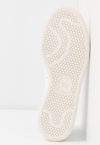 Weiße Sneaker-Sohle mit einem strukturierten Wabenmuster und einem markanten Adidas-Logo. Glattes Gummi mit konturiertem Fußbogenstütze.