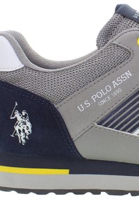 Sneaker con tomaia in mesh grigio e suede blu navy, presenta un logo bianco, dettagli gialli e suola nera. Design a righe sul materiale superiore.