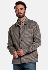 Veste à motif pied-de-poule marron et beige, avec une fermeture à boutons, une poche poitrine simple et un col standard. Tissu en mélange de coton.