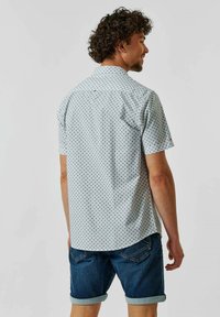 Korte mouw shirt in lichtblauw met kleine zwarte geometrische patronen, voorzien van een klassieke kraag en een licht gebogen zoom. Draag het met denim shorts.