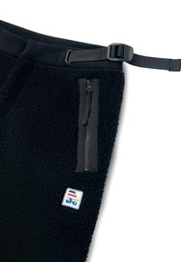 A fekete bolyhos nadrágok textúrált külsővel, állítható derékkal, fekete cipzáras zsebbel és egy kis hímzett logóval rendelkeznek.