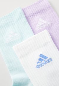 Tre par sokker: lys blå, hvit og lavendel, med ribbet tekstur og Adidas-logo i blått på den hvite sokken.