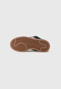 Shoe em tecido preto com sola de borracha, apresentando um padrão em zigue-zague. A sola é castanha clara e possui um design texturizado que melhora a aderência.