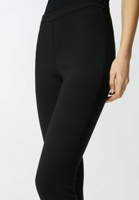 Leggings negros hechos de tela elástica, con una textura suave, diseño ajustado y sin elementos visibles ni estampados.