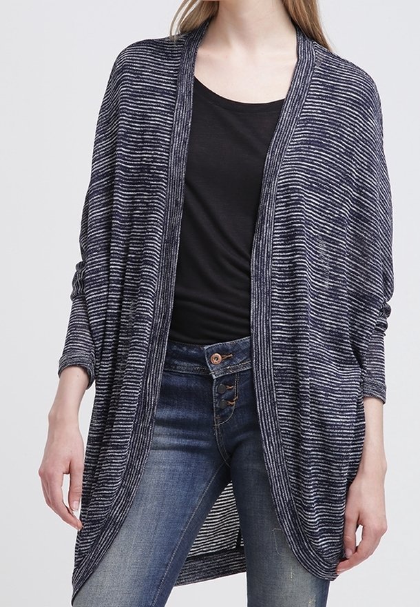 Cardigan leggero a righe navy con apertura frontale, maniche lunghe e design drappeggiato abbinato a un top nero e jeans blu.