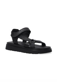 Schwarze Leder-Sandalen mit flacher Sohle, die über Kreuzriemen und einen verstellbaren Knöchelriemen verfügen. Die Textur ist glatt mit minimalen Details.