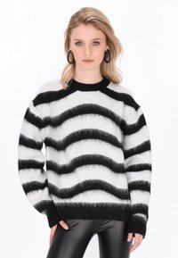 Zwart-wit gestreepte trui met een zachte, fluffy textuur. Heeft een ronde halslijn en lange mouwen. Gecombineerd met zwarte leren broeken.