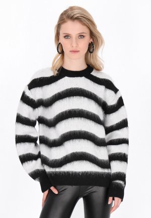 Pull rayé noir et blanc avec une texture douce et duveteuse. Présente un col rond et des manches longues. Assorti à un pantalon en cuir noir.