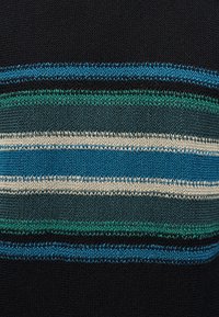 Bandes horizontales tricotées en bleu, vert, sarcelle, noir et crème sur un fond de tissu texturé.