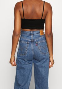 Blå denimjeans med hög midja och avslappnad passform, med läderpatch bak, dubbla bakfickor och subtila sömdetaljer.