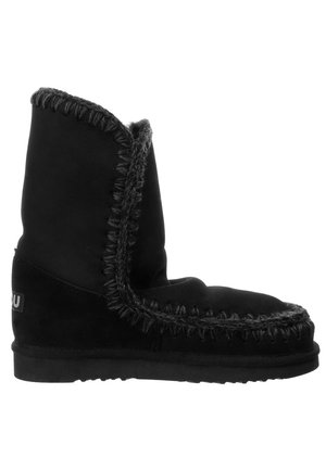 Stivaletti neri in suede con una texture morbida, caratterizzati da cuciture grigie a contrasto lungo le cuciture e una suola piatta.