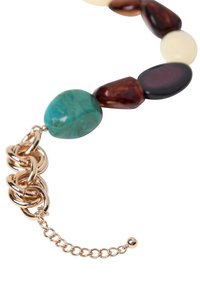 Bracciale chunky con pietre multicolori in tonalità di turchese, marrone e avorio, con una catena e un dettaglio di chiusura in tonalità dorata.
