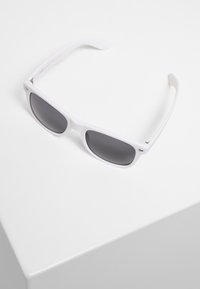 Ochelari de soare din plastic alb, cu lentile dreptunghiulare, având nuanță gri închis și brațe subțiri. Include un detaliu mic al logo-ului pe lateral.