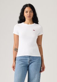 T-shirt blanc à manches courtes en coton avec col rond et petit logo rouge Levi's sur la poitrine gauche. Présente un design ajusté.
