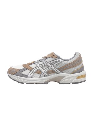 Zapatilla deportiva con parte superior de malla blanca, acentos de ante gris y detalles plateados. Cuenta con una suela acolchada y una puntera reforzada.