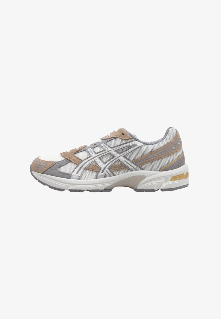 Sneaker atletico con una parte superiore in mesh bianco, dettagli in suede grigio e rifiniture argentate. Presenta una suola imbottita e una punta rinforzata.